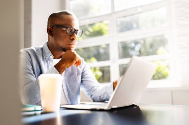 Genç Afrikalı Amerikalı iş adamı hukuk bürosunda dizüstü bilgisayarla hukuk davalarını araştırıyor hukuk firması için iş stratejileri geliştiriyor..