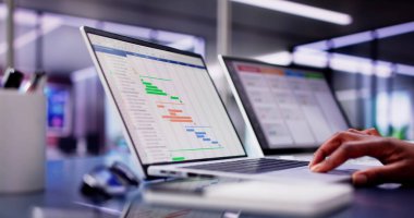 Modern ofis ortamında birden fazla iş ve proje yürütmek için dizüstü bilgisayar kullanan Afro-Amerikalı bir kadın. Meşgul iş profesyoneli.