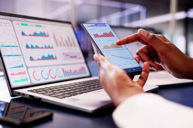 Afrikalı Finansal Danışman dizüstü bilgisayarındaki borsa eğilimlerini izlemek için analitik grafikleri olan bir KPI gösterge paneli kullanıyor..