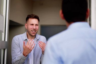 Girişte İspanyol komşusuyla tartışan stresli genç bir adam oturma odasının duvarında bir anlaşmazlığı tartışıyor..