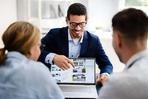 stock image Professional Real Estate Agent Presenting Property Options to Happy Couple Using Laptop in Modern Office Setting