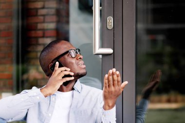 Hüsrana uğramış Afrikalı Amerikalı Adam Evden Dışlandı, Çilingir için Bekliyor, Akıllı Telefon Yardım Uygulaması Kullanıyor.