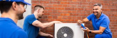 Tecrübeli HVAC teknisyeni bakım ve montaj hizmetleri yapıyor, ticari iş ortaklığı yapan bir ekiple elektrik sistemlerini denetliyor..