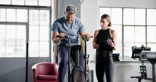 Cardio Workout In Gym On Elliptical Bike Machine With Personal Trainer