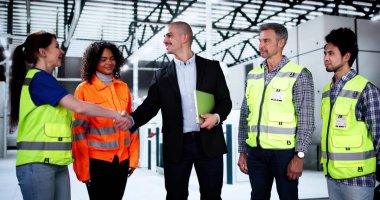 Fabrika mühendisleri ve çeşitli işçi grupları el sıkışıyor.