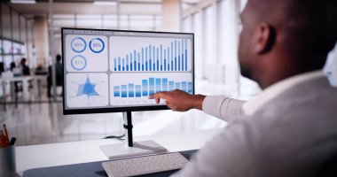 Hybrid Ofis 'teki dizüstü bilgisayardaki Finansal Verileri analiz eden Afrikalı Amerikalı Adam Dijital Girişimcilik KPI Kontrol Paneli Ayarlıyor.
