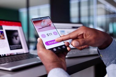 Afrikalı Amerikalı adam internet üzerinden para bağışlamak, hayır kurumlarını desteklemek ve finans fonlarına yatırım yapmak için akıllı telefon uygulaması kullanıyor..