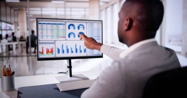 Hybrid Ofis 'teki dizüstü bilgisayardaki Finansal Verileri analiz eden Afrikalı Amerikalı Adam Dijital Girişimcilik KPI Kontrol Paneli Ayarlıyor.