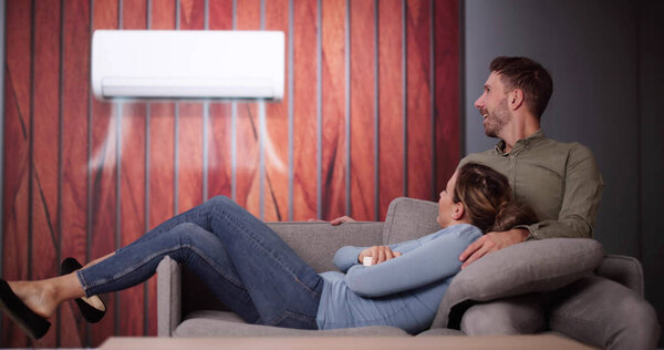 Happy Family Couple Using Air Conditioner. Apartment AC