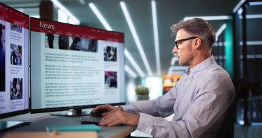 Çevrimiçi gazetede haberlere bakan adam bilgisayarda