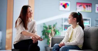 Genç bayan çocuk terapisti terapi seansı sırasında depresyondaki bir çocuğu rahatlatıyor. Muhtemel meslekler: terapist, doktor, hemşire, sosyal hizmet görevlisi, psikolog.