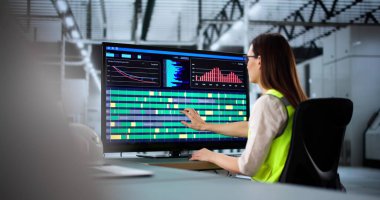 Genç mühendis fabrikada üretim hattını yönetmek için bilgisayar kullanıyor. Gelişmiş otomatikleştirilmiş fabrikada enerji tasarruflu sistemleri bağlayan kadın teknisyen..  