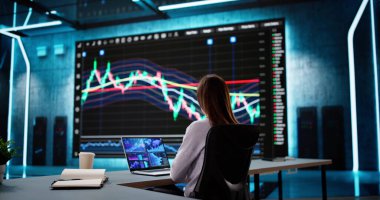 Bilgisayar Ekranındaki Hisse Verilerinin Analizi: Finans Ofisindeki İş Kadını.