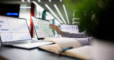 Modern ofiste finansal verileri yöneten genç bir kadın..