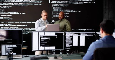 Ofisteki bilgisayarlarda kodlama yapan çeşitli yazılım mühendisleri grubu.