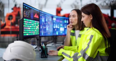 Kadın mühendis modern fabrika ortamında otomatik üretim sistemini izliyor.