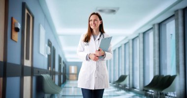 Kadın cerrah hastane koridorundaki personele dijital tablet kullanarak danışmanlık yapıyor..