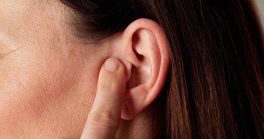 Kadın işitme cihazı tutuyor, kulak ağrısı çekiyor. Audiolog mesleği.