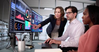 Çeşitli öğrenci grupları bilgisayar ekranlarında iş analizi öğreniyor.