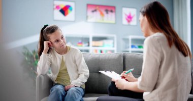 Psikiyatrist terapi seansı sırasında üzgün hiperaktif çocuğu rahatlatıyor..