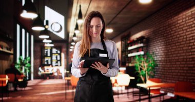 Meşgul restoran garsonu müşterilere gülümseme ve verimlilik sunuyor. Küçük işletme sahibi onun gelişmekte olan dükkanında gururla duruyor.. 