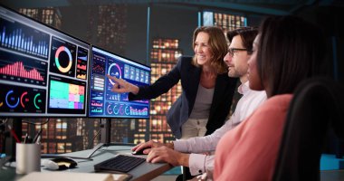 Öğrenciler ve öğretmenler bilgisayar ekranlarında çeşitli verileri analiz ederek, iş başarısını öngörüyorlar.