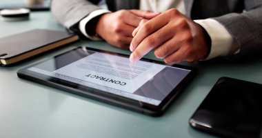 Ofisteki bilgisayarda sözleşmeyi gözden geçiren odaklanmış genç adam..