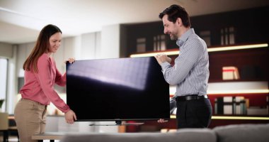 Çift ferah oturma odasında yeni bir televizyon kuruyor..