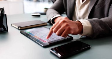 Ofisteki tablette dijital takvim kullanan Afrikalı Amerikalı bir adam.