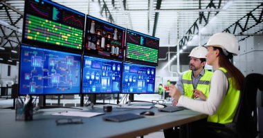 Kadın ve erkek SCADA sistemini izlemek için kontrol yazılımı kullanıyor.