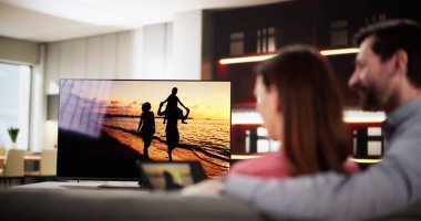 Adam rahat oturma odasında tabletten televizyona video yayınlıyor. İç mimar, pazarlama otomasyon uzmanı