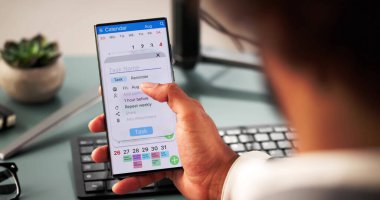 Genç Afrikalı Amerikalı adam dizüstü bilgisayar ve akıllı telefondan program düzenliyor..