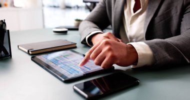 Genç Afrikalı Amerikalı adam bilgisayar tablosu yazılımındaki verileri analiz ediyor.