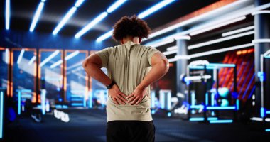 Spor salonunda sırtı ağrıyan siyah bir adam sağlık hizmeti istiyor..