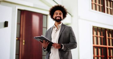 Siyahi Afro-Amerikalı adam, ipotek sözleşmesi için gayrimenkul değerlendirmesi yapıyor.