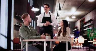 Yıldönümünü kutlayan adam ve kadın şık yemek masasında oturuyor..