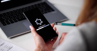 Teknolojiden anlayan kadın iş yerindeki akıllı telefonunda yazılım güncellemesi kuruyor