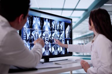 Doktor, hastanedeki bilgisayar ekranında dizlerin röntgen görüntülerini analiz ediyor.