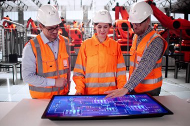 Erkek ve kadın otomobil fabrikasında üretim yapan bilgisayarları kullanıyor..