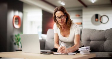 Evde Kanepede Çevrimiçi Finans Çalışan Kadın Faturaları Hesaplıyor.