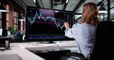 Şirket ofisindeki hisseleri takas etmek için bilgisayar kullanan profesyonel bir iş kadını.