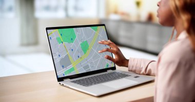 Şehirdeki laptopta gayrimenkul ilanlarına göz atan Afro-Amerikalı kadın..