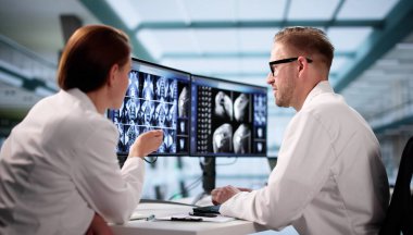 Nörolog, hastanedeki çeşitli bilgisayar monitörlerinde beyin taramalarını analiz ediyor..