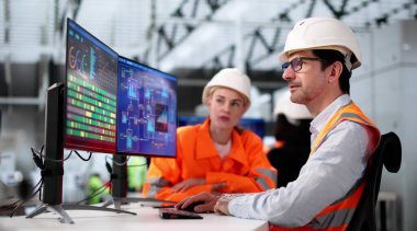 Fabrika işçilerinden oluşan çeşitli ekip imalat tesisinde bilgisayar kullanıyor.