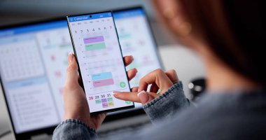 Laptop ve telefondaki randevuları ve programları düzenleyen meşgul bir iş kadını..