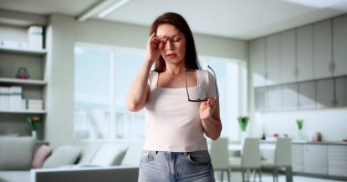 Gözlüklü akıllı kadın kaşıntılı gözlerini kederle ovuşturdu..