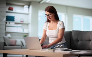 Koltukta otururken bilgisayarda finans hesapları yapan genç kadın.