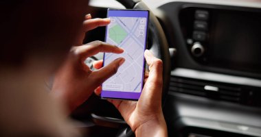 Kadın lüks bir arabada gezinirken telefondaki GPS 'in haritasını çıkarıyor. Olası Meslekler: Araba satıcısı, Emlakçı