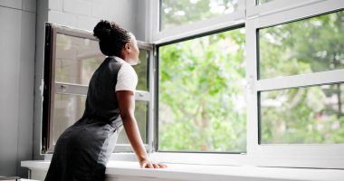 Genç Afrikalı Amerikalı Kadın Temiz hava almak için pencereyi açıyor