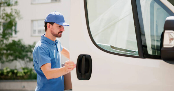 Счастливый почтальон достает посылку из грузовика для сервисной компании.